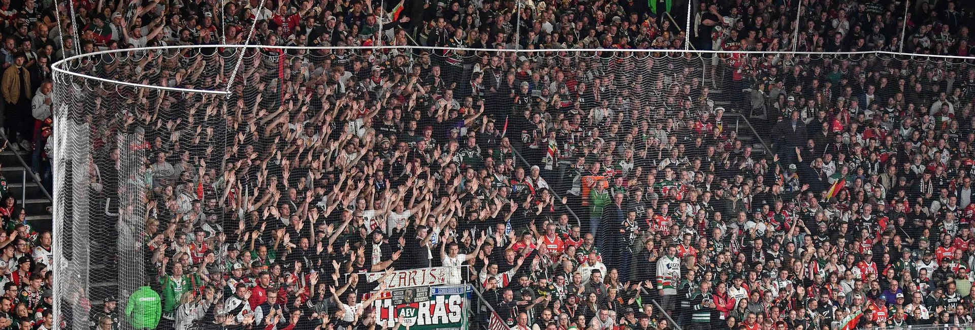 Ein Foto in den Fanblock der Augsburger Panther. Ein Teil der Zuschauer hält die Armbe zum Anfeuern hoch.